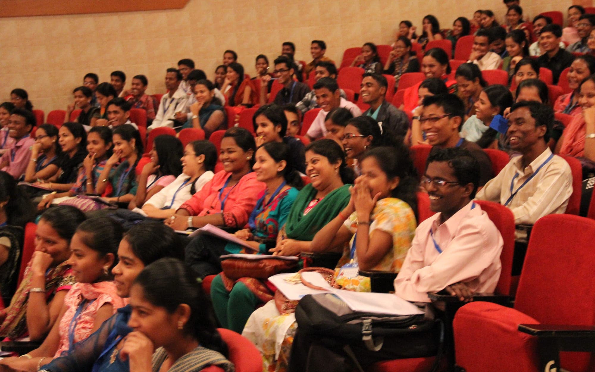 College students laughing in an auditorium during a workshop session in Maharashtra